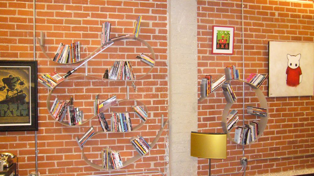 A book collection on a Ron Arad Bookworm shelf, lightsaber included